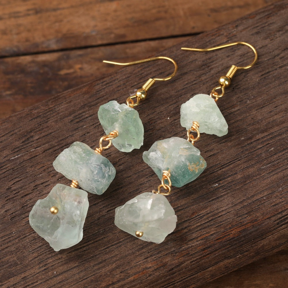 Experience the beauty of nature with Fiong Mma&#39;s Raw Crystal Earrings- A pair of our exquisitely designed Raw Crystal Earrings, handcrafted from a variety of 24 natural stones. Each earring showcases the unique textures and colors of the stones, offering a blend of fashion and natural beauty, and reflecting a deep connection to the Earth.