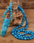 Mala bead necklace made with a unique design and gemstones. The necklace has mala beads arranged in a loop, with a gemstone pendant hanging from the center. The intricate knotting and weaving techniques used in the design can be seen, giving the necklace a handmade and artisanal feel. The image captures the beauty and spiritual significance of the mala necklace, which serves as a meaningful tool for meditation and spiritual practices.