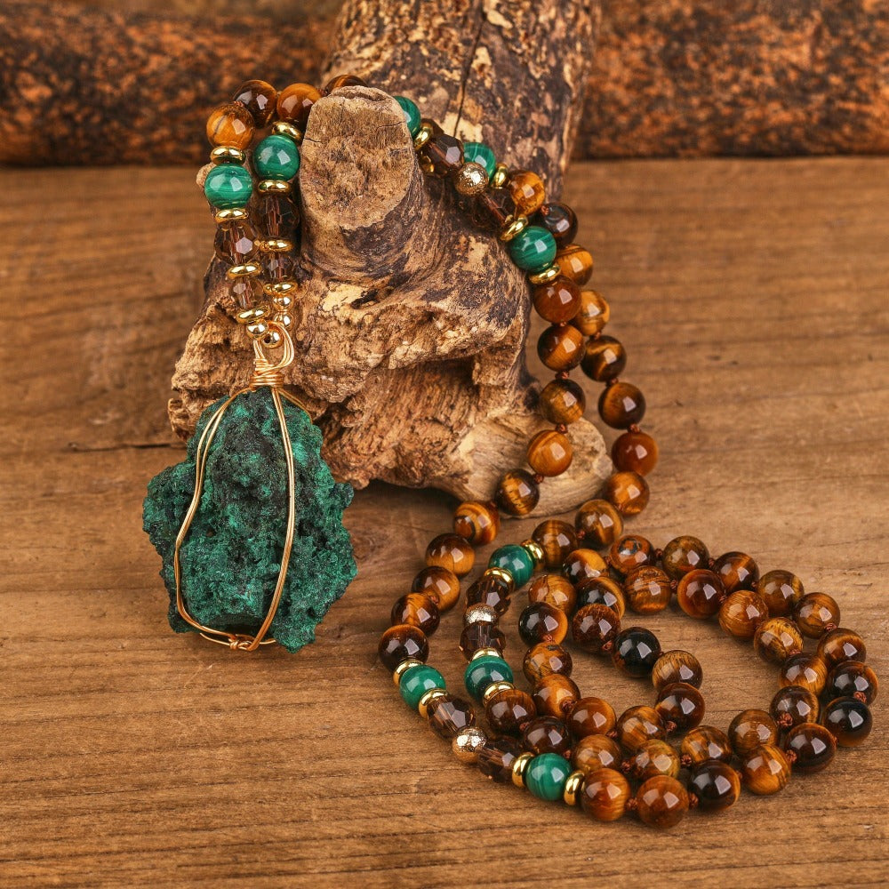Mala bead necklace made with a unique design and gemstones. The necklace has mala beads arranged in a loop, with a gemstone pendant hanging from the center. The intricate knotting and weaving techniques used in the design can be seen, giving the necklace a handmade and artisanal feel. The image captures the beauty and spiritual significance of the mala necklace, which serves as a meaningful tool for meditation and spiritual practices.